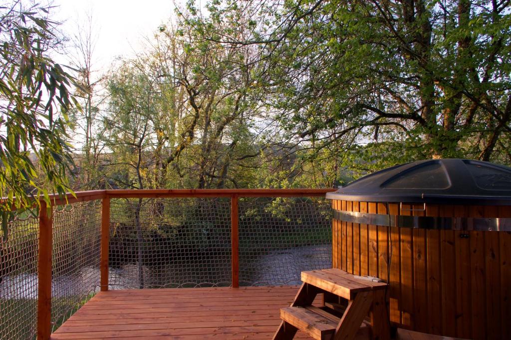 a wooden deck with a wooden barrel and a bench at Chalet des Aigrettes, Les 1000 Etangs in La Voivre