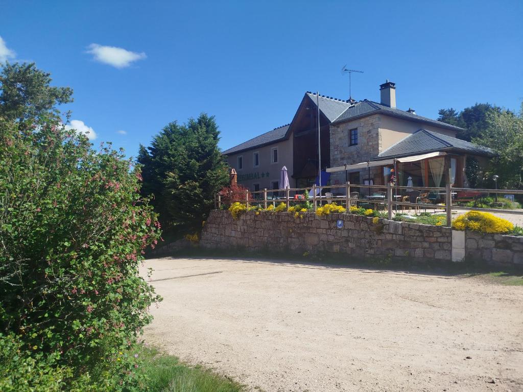 a house with a stone retaining wall and a yard at Hôtel Restaurant Le Regimbal in Javols