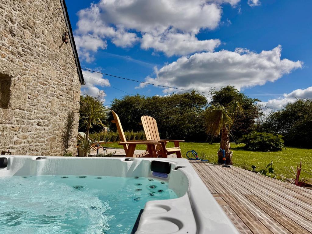 a hot tub on the deck of a house at Maison de Charme avec Spa Privatif & Jardin en Pleine Nature - Plages à moins de 20min in Guerlesquin