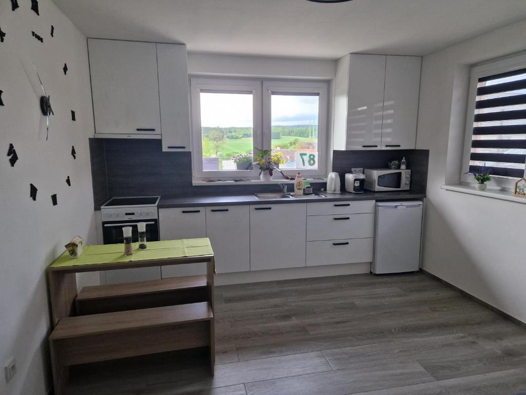 a kitchen with white cabinets and a table in it at Vejminek 87 in Červená Třemešná