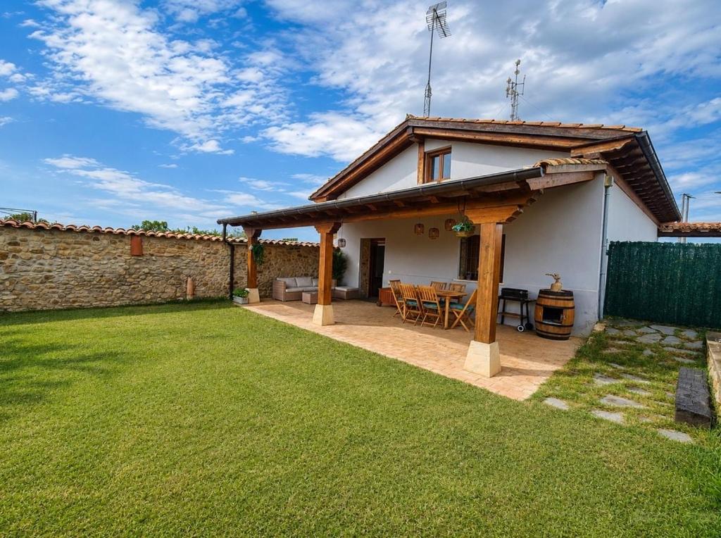 a house with a patio and a grass yard at La Cochera del Abuelo in Medina de Pomar