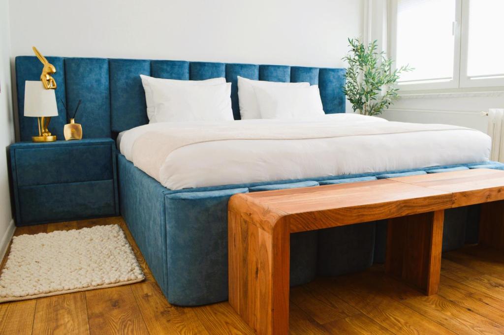 a bed with a blue headboard and a wooden bench at Apartman Vera in Prijedor