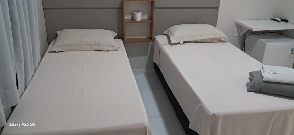 two beds in a small room with white walls at hOTEL CALIFORNIA in Barreiras