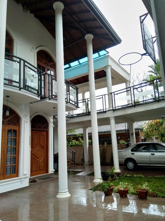 a car parked in front of a house with columns at D & N Homes- Villa 1 in Kalutara