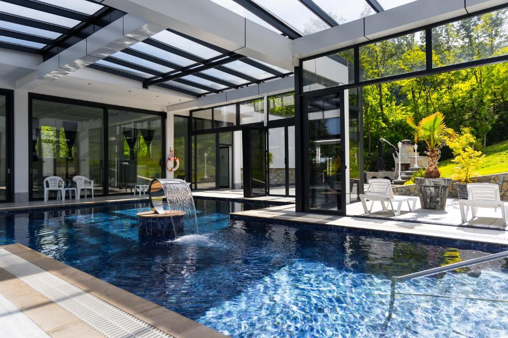a swimming pool in a house with glass walls at White House Radac Peja in Peje