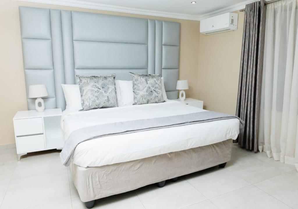 a white bedroom with a large bed with a blue headboard at Kunjalo Lodge in Inadan