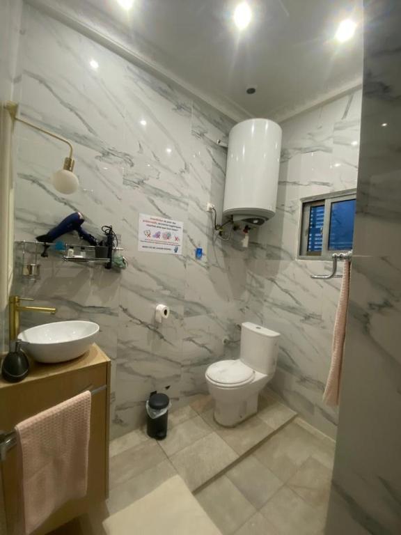 a white bathroom with a toilet and a sink at La Bienveillance in Brazzaville