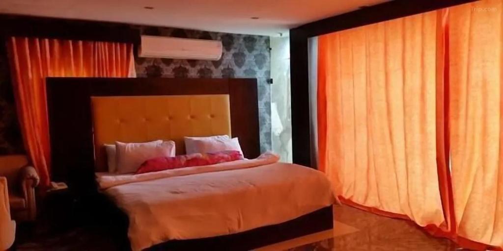 a bedroom with a bed with orange curtains at Paris Suites in Festac Town