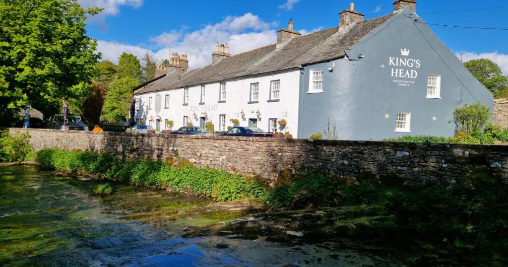 a building next to a river next to a bridge at Kings Head - Riverside, Ravenstonedale in Ravenstonedale