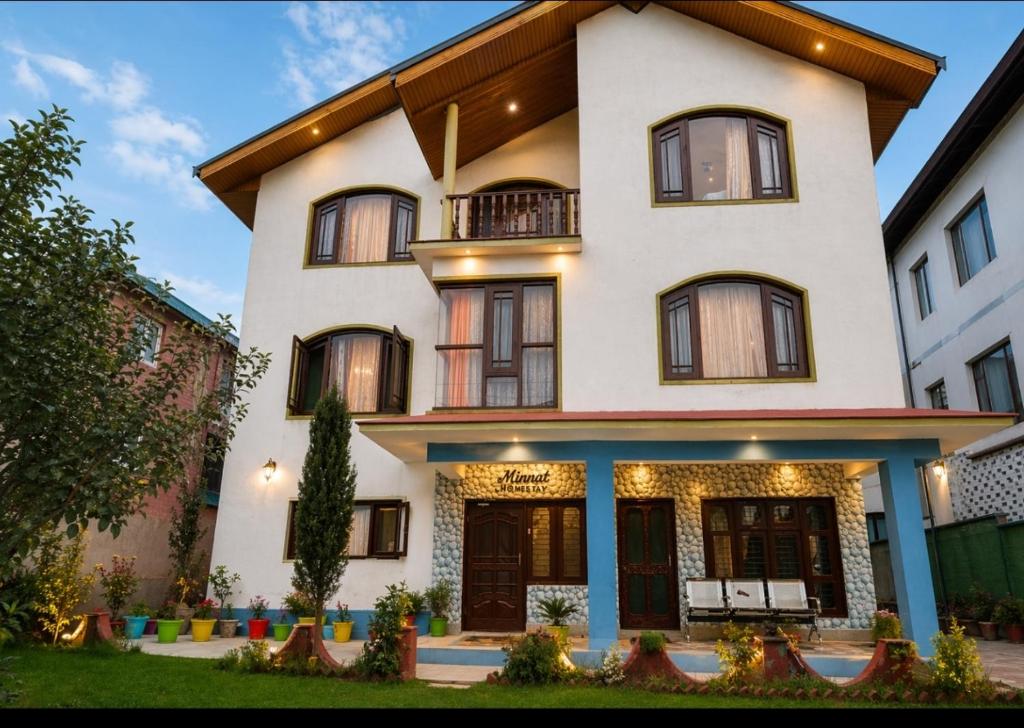 a large white house with a porch at Minnat Home Stay in Srinagar