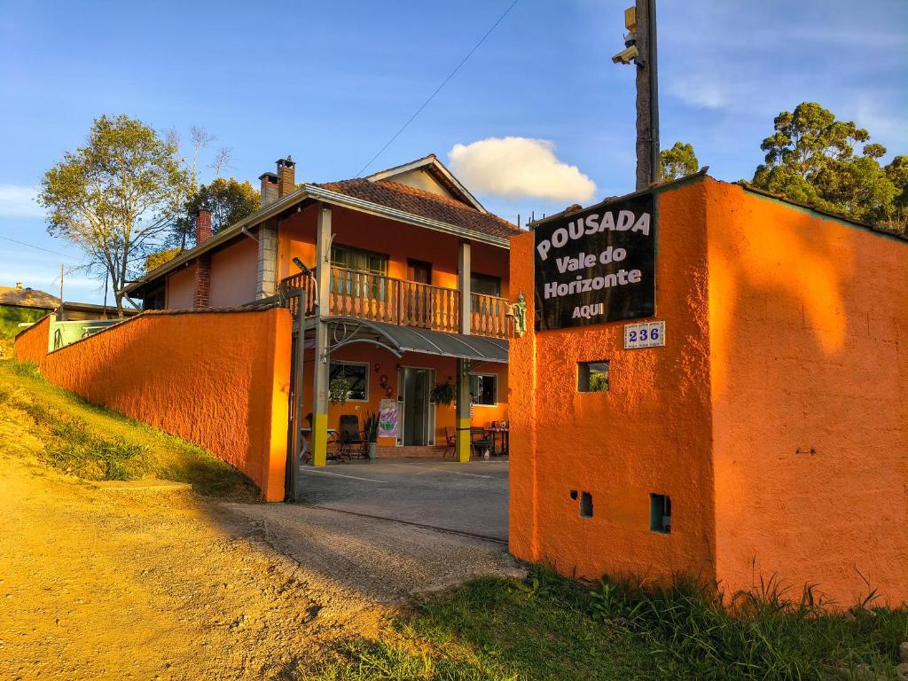 an orange building with a sign on the side of it at Pousada Vale do Horizonte in Monte Verde
