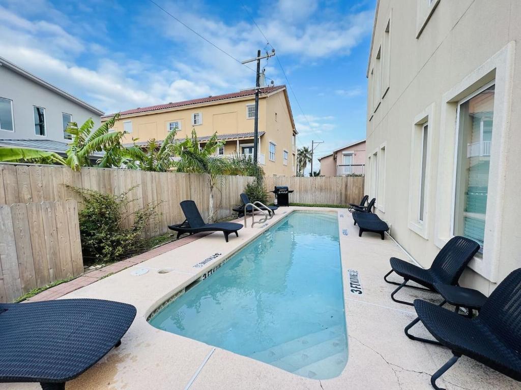 a swimming pool with chairs and a fence at Family Retreat with pool for 6 Pet Lovers 130 E Retama #3 in South Padre Island