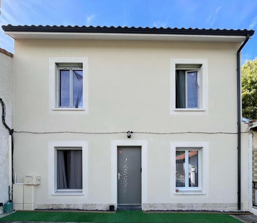 a white house with a black door at Cosytel in Bègles
