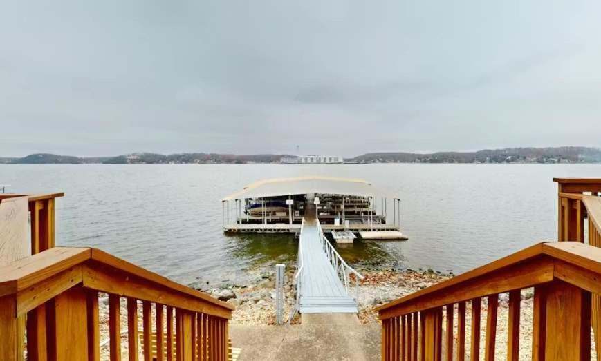a dock on a lake with a boat in the water at Lake Front Lookout in Lake Ozark