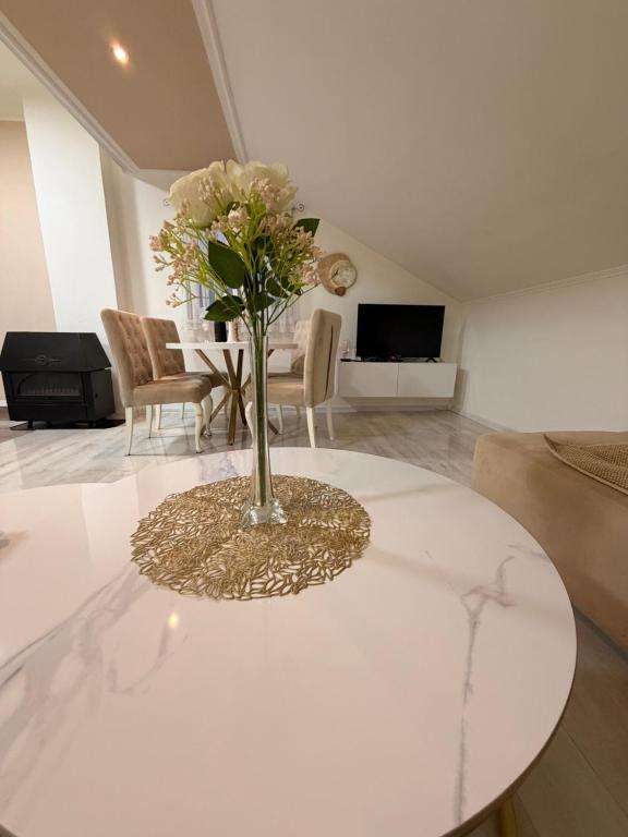 a vase of flowers on a white table in a living room at Apartman Maja in Prijedor