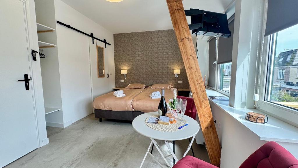 a small room with a bed and a table with a stool at Stationbeds Studio-2 Alkmaar in Alkmaar