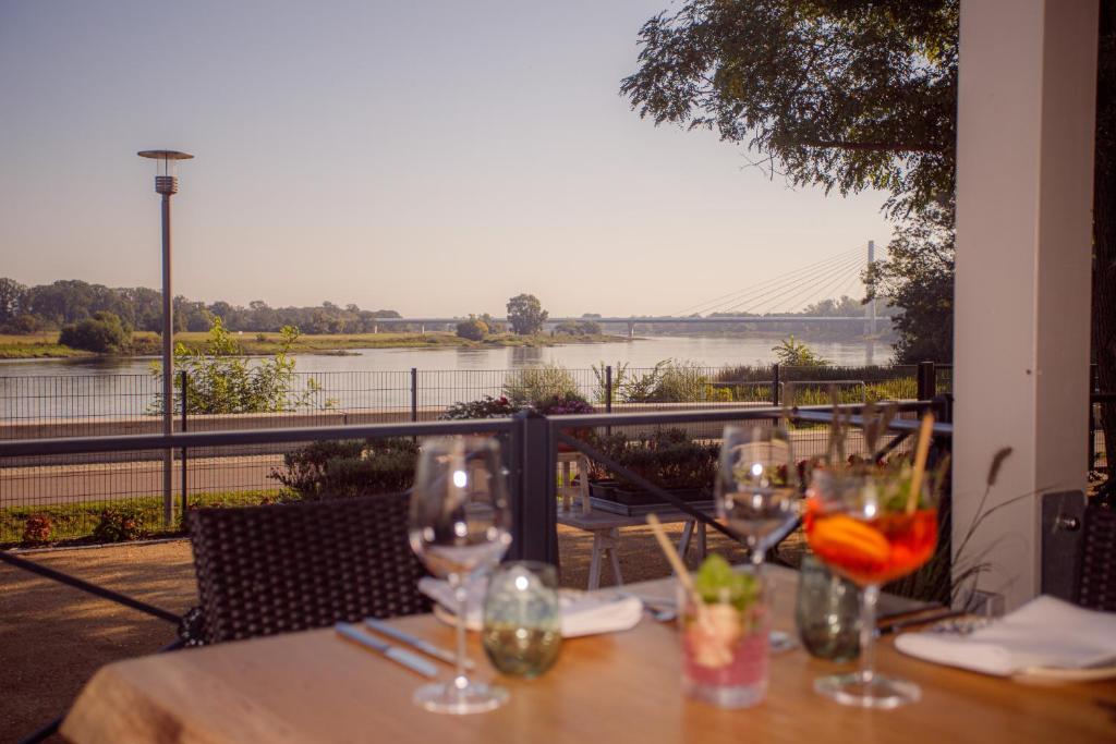 a table with wine glasses and a view of a river at WELTRAD Parkhotel am Fluss in Schönebeck