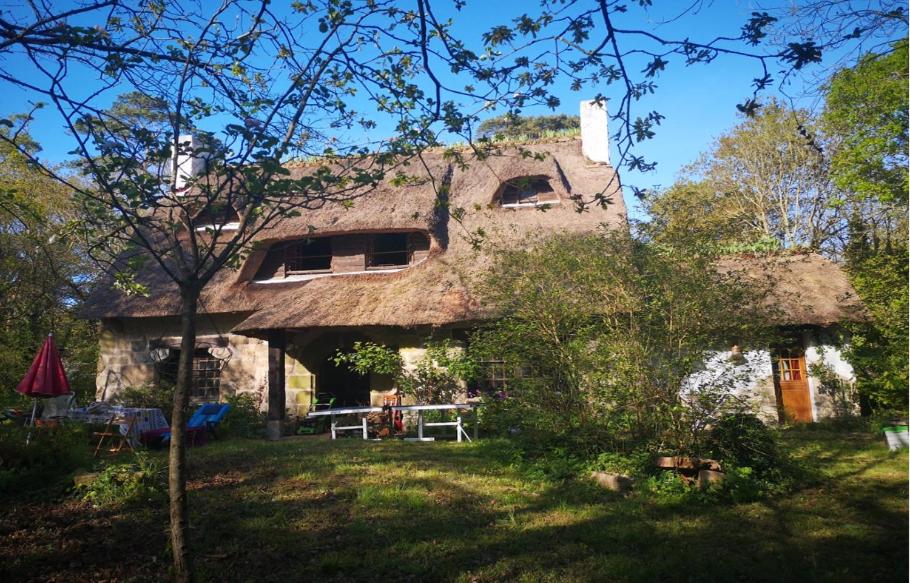 an old house with a thatch roof with a yard at La Chaumière in Fréhel