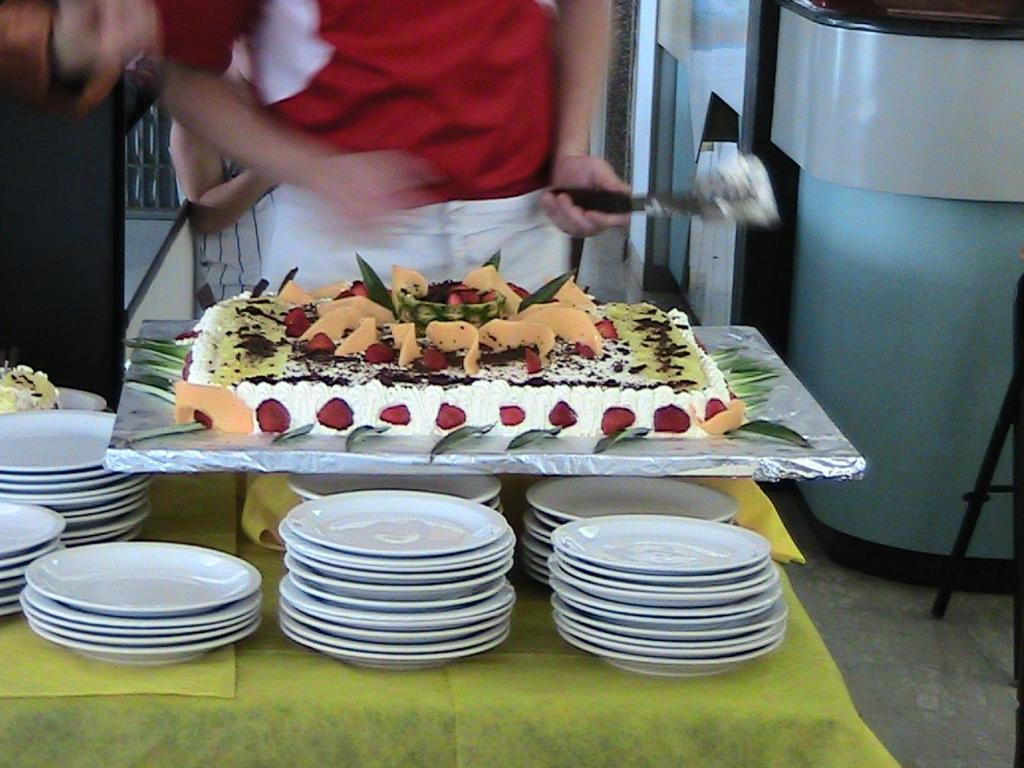 a person is cutting a cake on a table with plates at Hotel Universo in Rimini