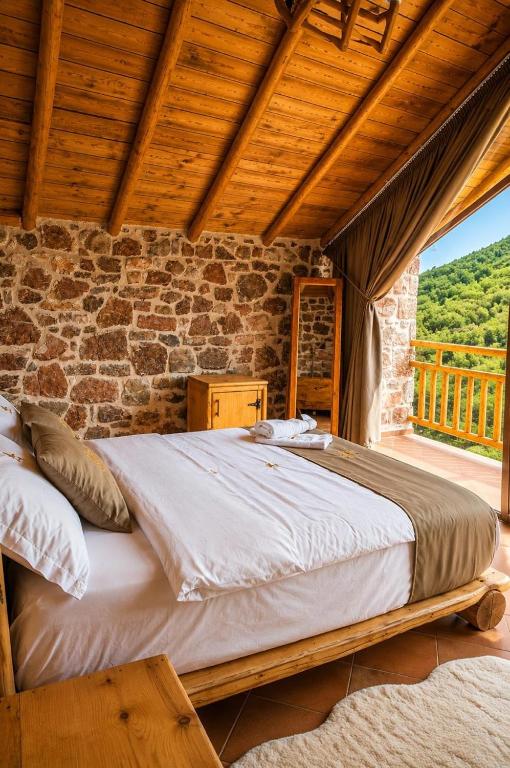 a bed in a room with a stone wall at Villa Lugina e Kuajve Bulqize in Bulqizë