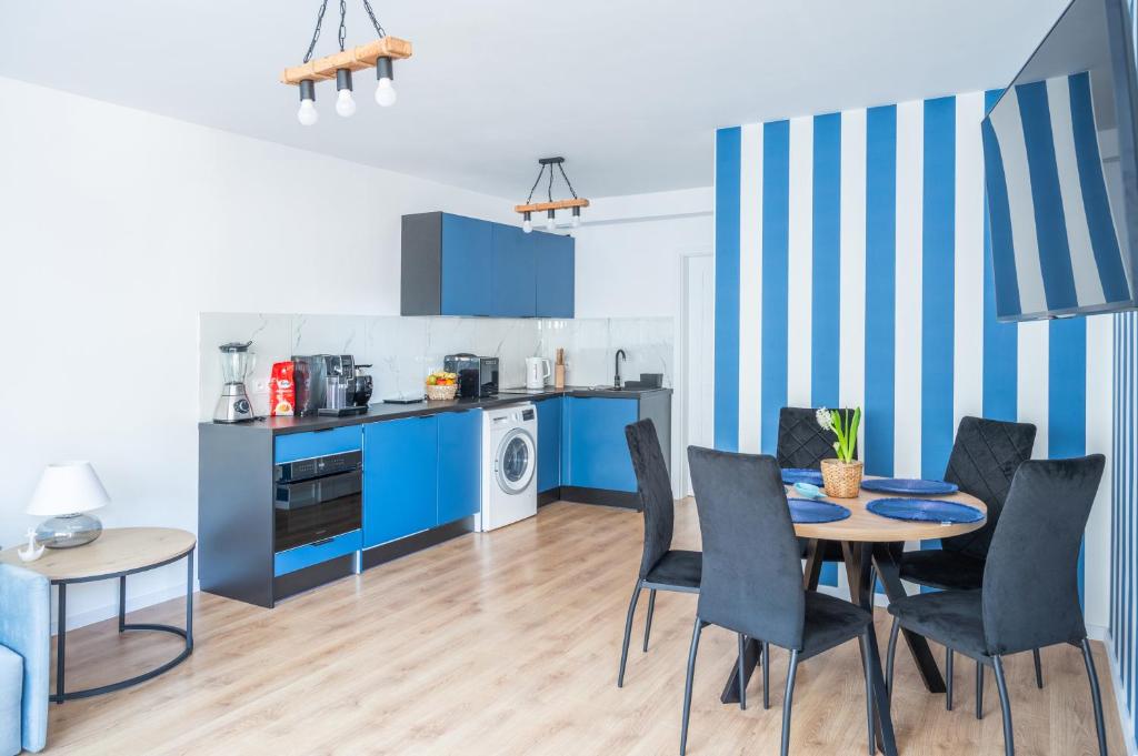 a kitchen with blue cabinets and a table and chairs at Nadmorski Bursztyn - Błękitna in Rowy