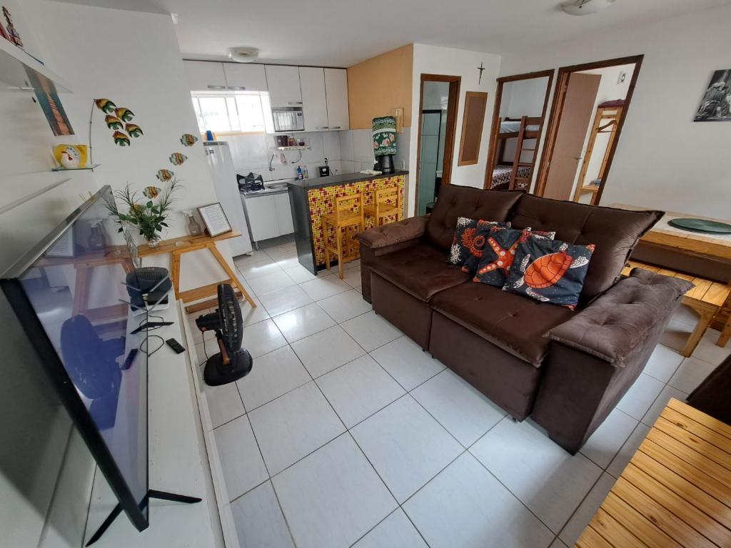 a living room with a brown couch and a kitchen at Apartamento Enseada Beach Residence completo in Cabo de Santo Agostinho