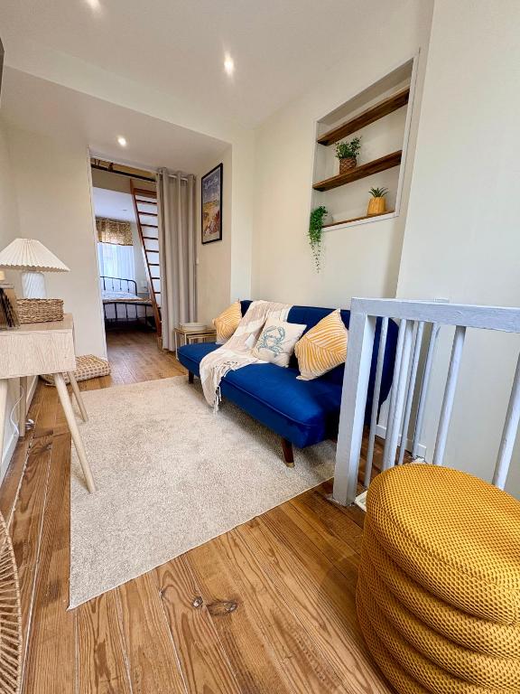 a living room with a blue couch and wooden floors at L'Échappée iodée à "La Cahute" - Rénovée, Calme & Proche Mer in Ambleteuse