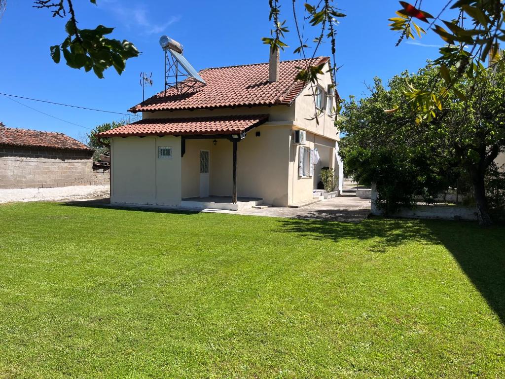 a house with a green lawn in front of it at Eleni village House in Kamena Vourla