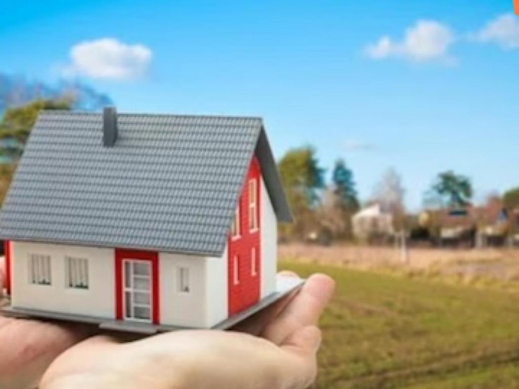 a hand holding a small model of a red and white house at Rishi niwas in Darbhanga