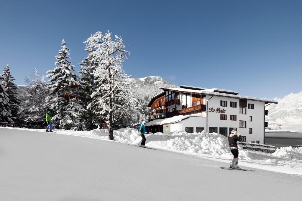 a group of people skiing in the snow in front of a building at Hotel La Perla: The Leading Hotels of the World in Corvara in Badia