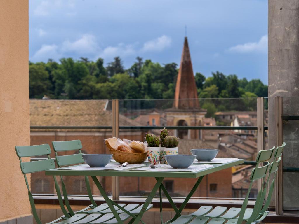a table on a balcony with a view of a church at Testa tra le Nuvole - Attico con Terrazza panoramica in centro in Novi Ligure