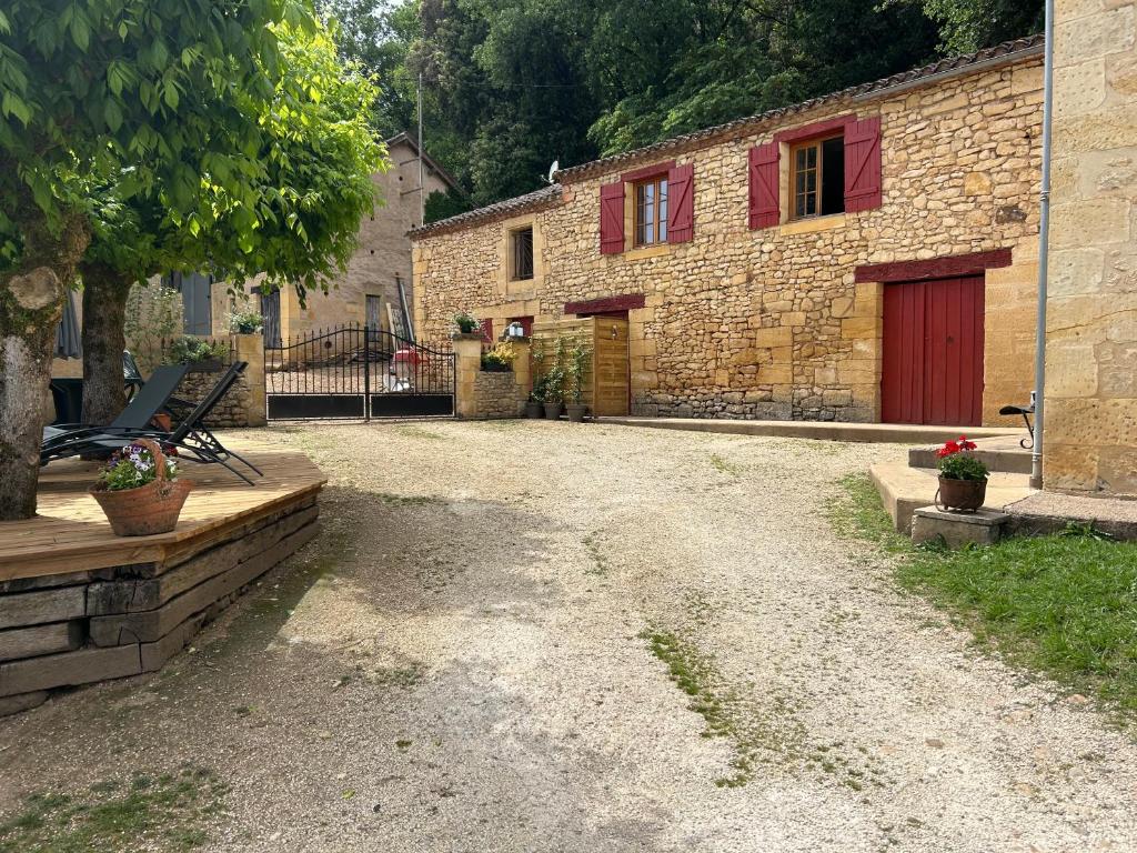 a stone house with red doors and a gravel driveway at GÎte à la ferme in Lalinde