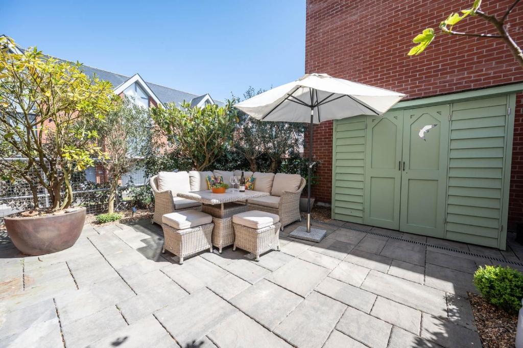 a patio with a table and an umbrella at Orange House, Southwold in Southwold