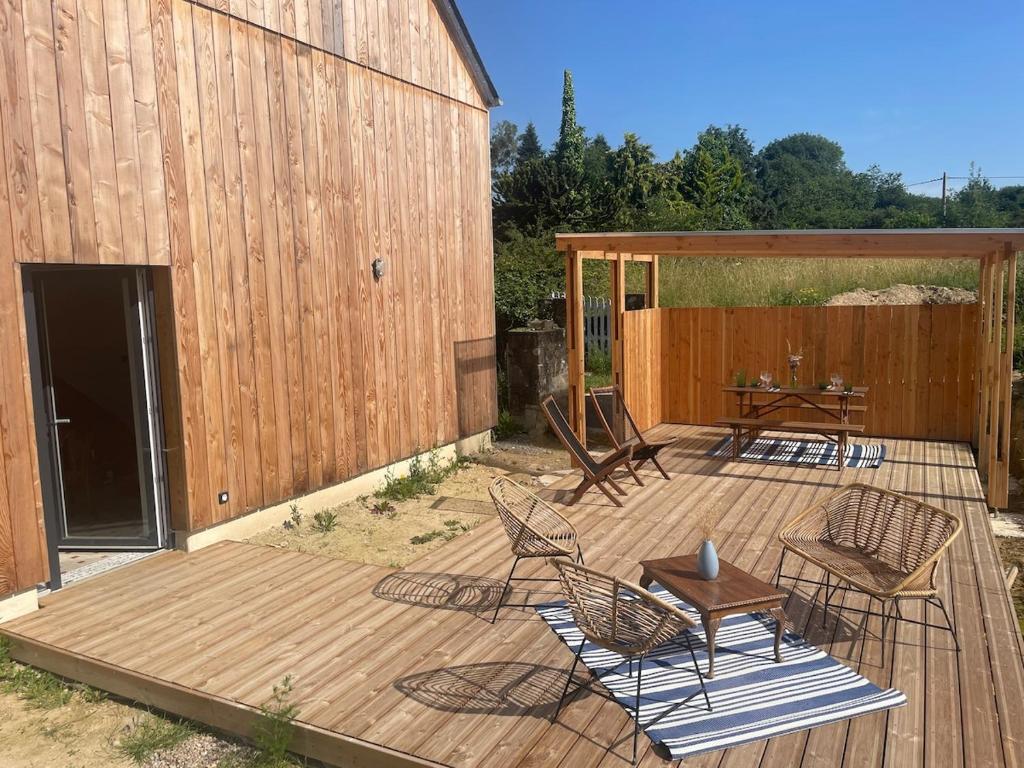 a wooden deck with chairs and a table next to a barn at La maisonnette in Saussemesnil