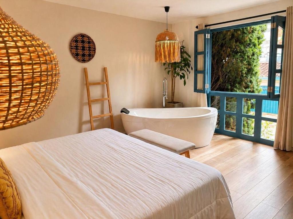 a bathroom with a tub and a bed and a window at Poblado Luum Boutique hotel in Medellín