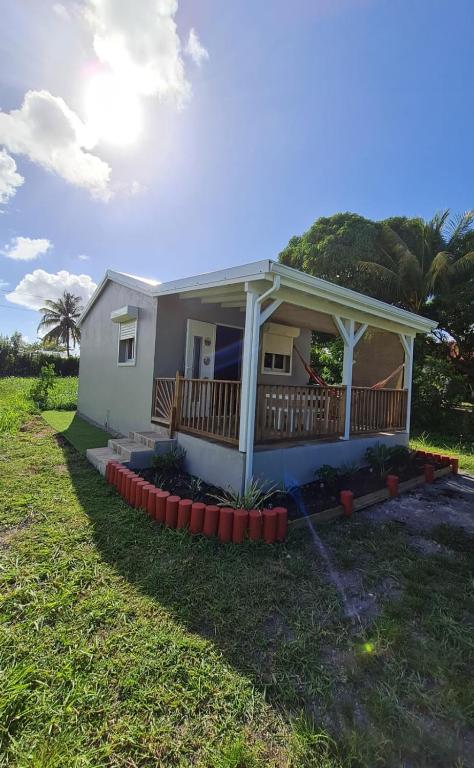 a small white house with a deck on a lawn at Canopée Créole in Petit-Canal