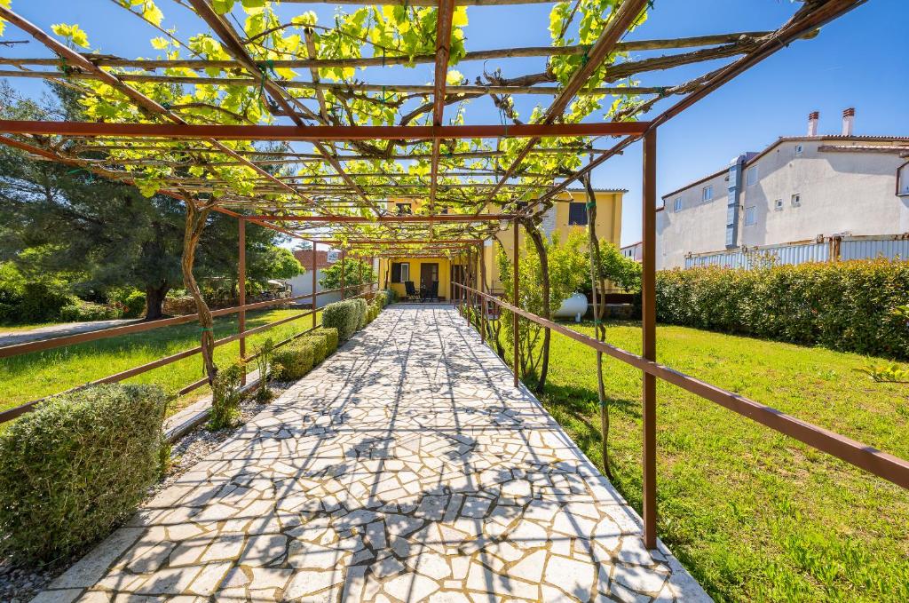 a walkway with a pergola in a yard at Garden House Premantura in Premantura