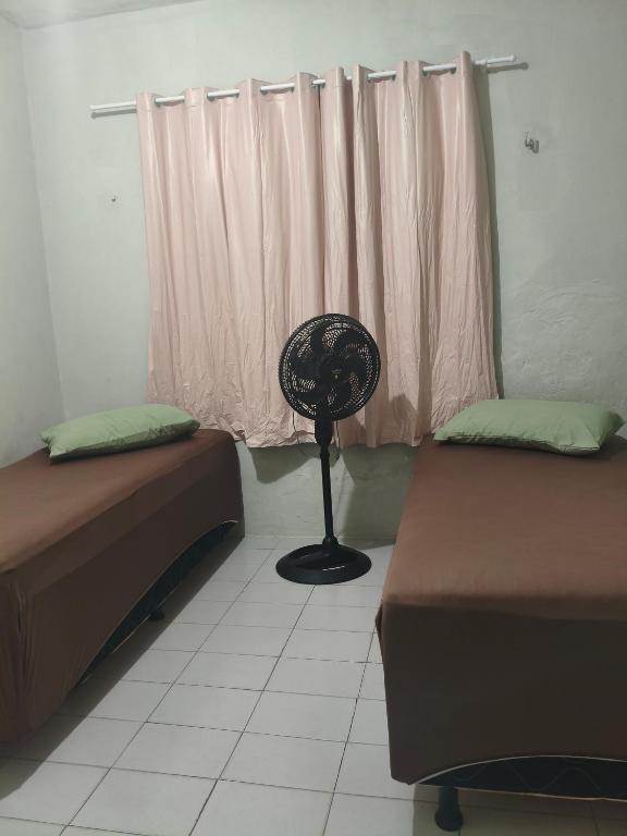 a room with two beds and a fan next to a window at Pousada Bom Jesuss in Juazeiro do Norte