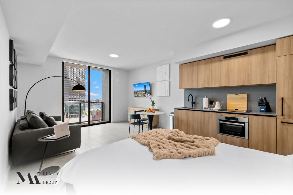 a white bedroom with a large bed and a kitchen at Walking Distance from Bayside Market Place - 501 First Residences Junior Studio Rooftop Pool in Miami