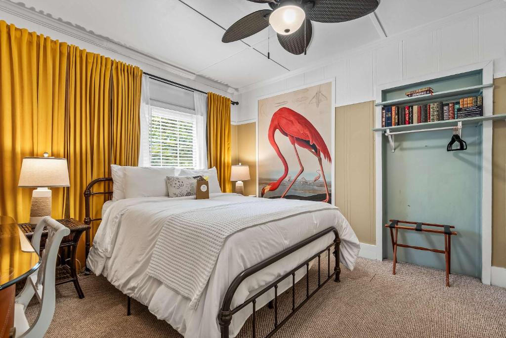 a bedroom with a large bed with a flamingo painting on the wall at Old Carrabelle Hotel Flamingo Suite in Carrabelle