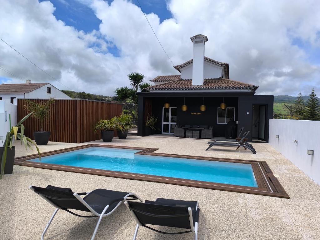 a swimming pool with two chairs and a house at Espaço Roteiro de Mimos in São Vicente Ferreira