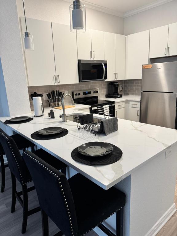a kitchen with a large white island with black chairs at The Experience in Houston