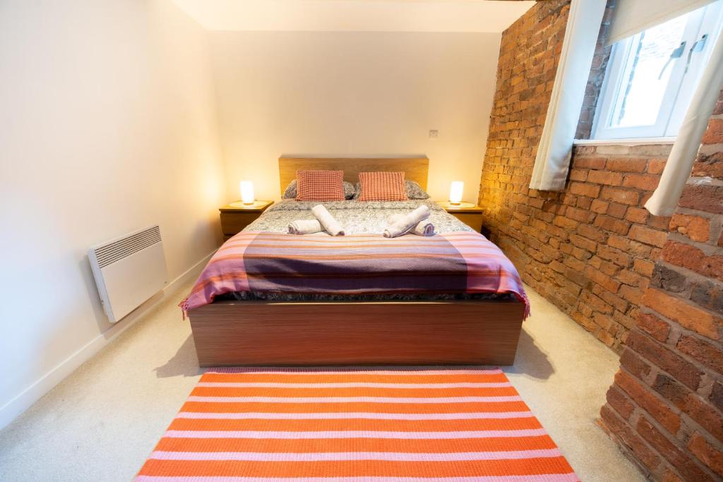 a bedroom with a bed and a brick wall at Rustic 2BR Loft Exposed Brick & Beams in Liverpool