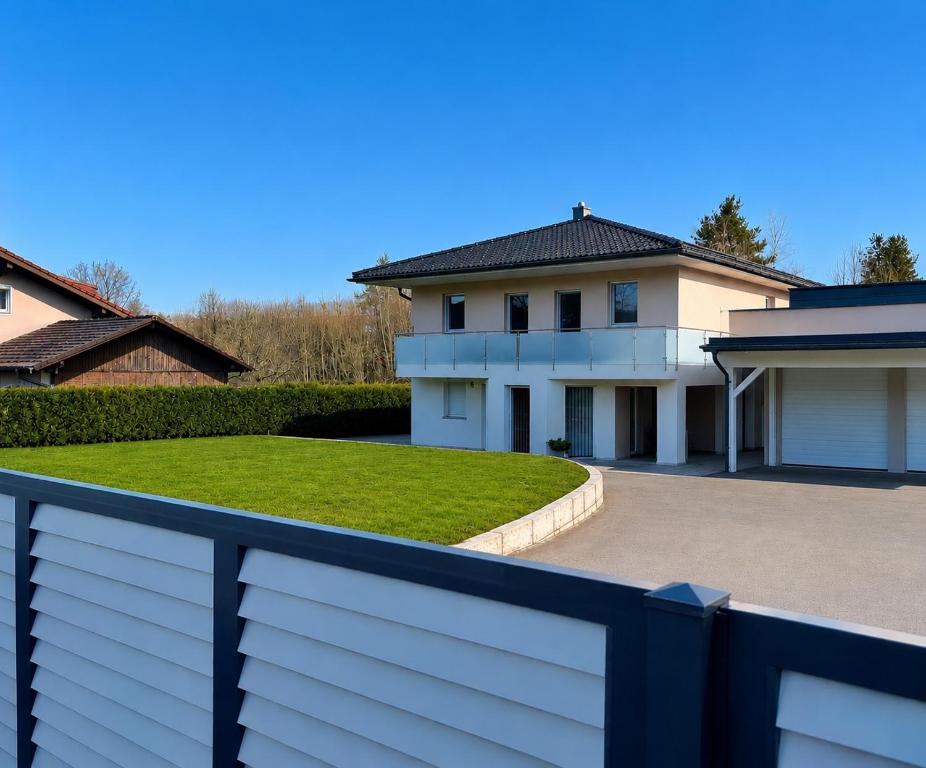 a house with a white fence and a yard at AJRooms in Velden am Wörthersee