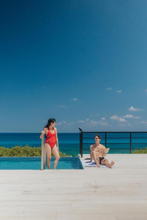 a man and a woman standing next to a swimming pool at Sierra Mar in Isla Mujeres