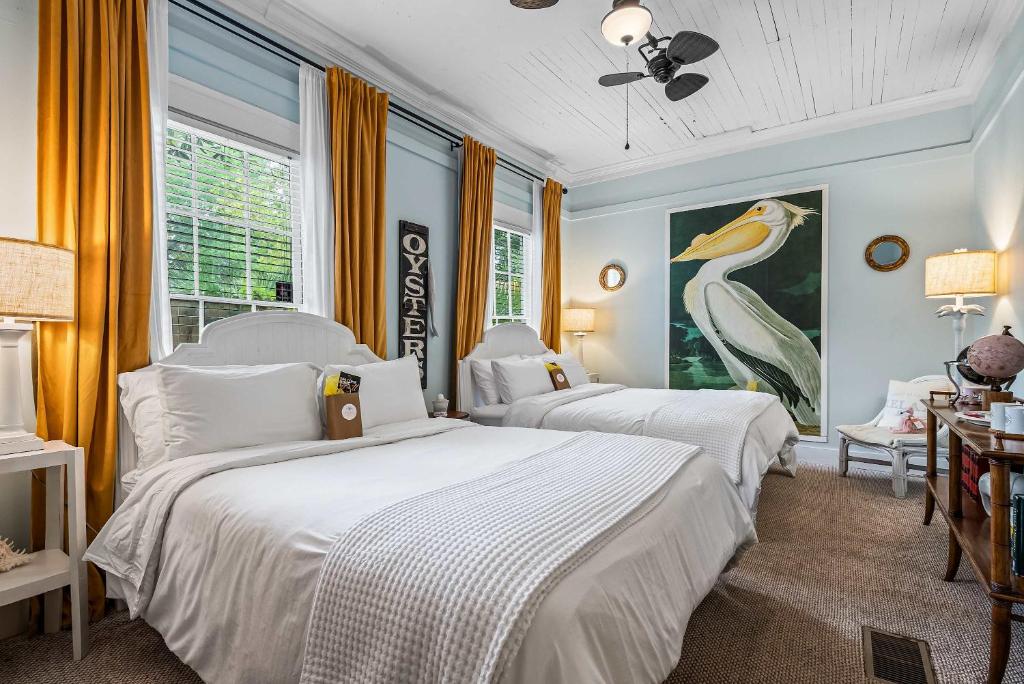 a bedroom with two beds and a painting of a bird at Old Carrabelle Hotel Captains Quarters Suite in Carrabelle