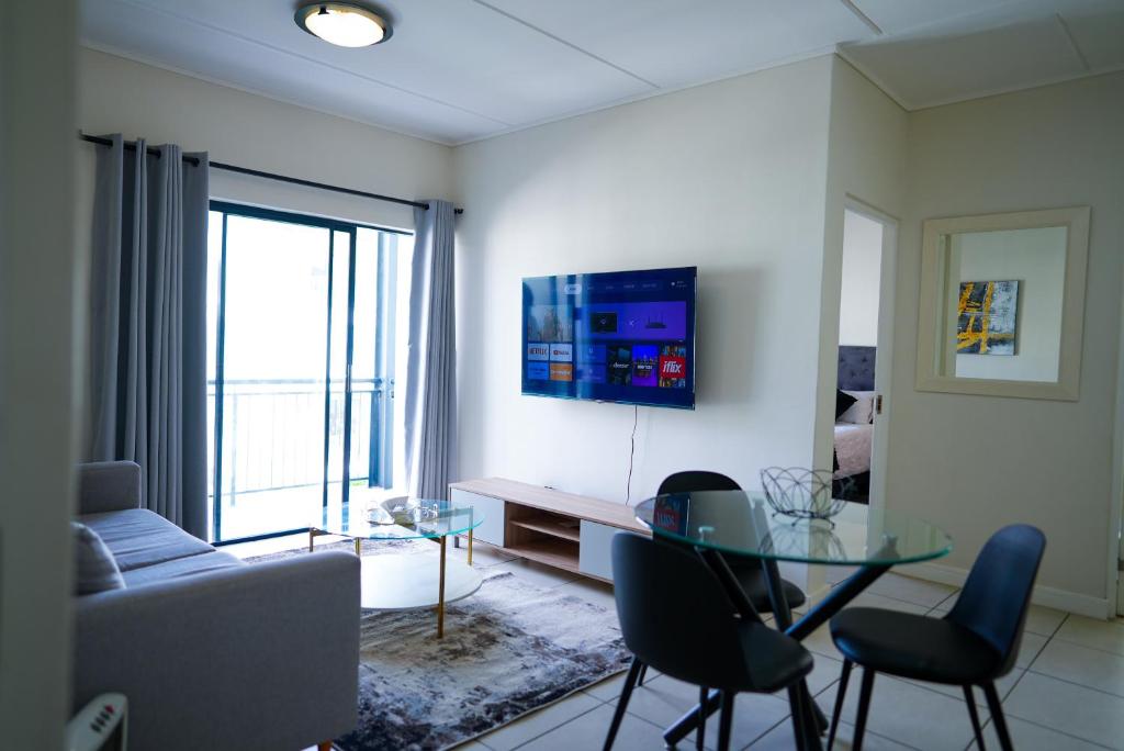 a living room with a couch and a table and chairs at Fynbos Lifestyle Estate - One Bed Apartment in Cape Town