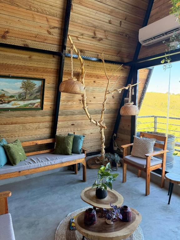 a living room with wooden walls and benches and swings at Alpine Cabin PR 2026 in Tavera Abajo