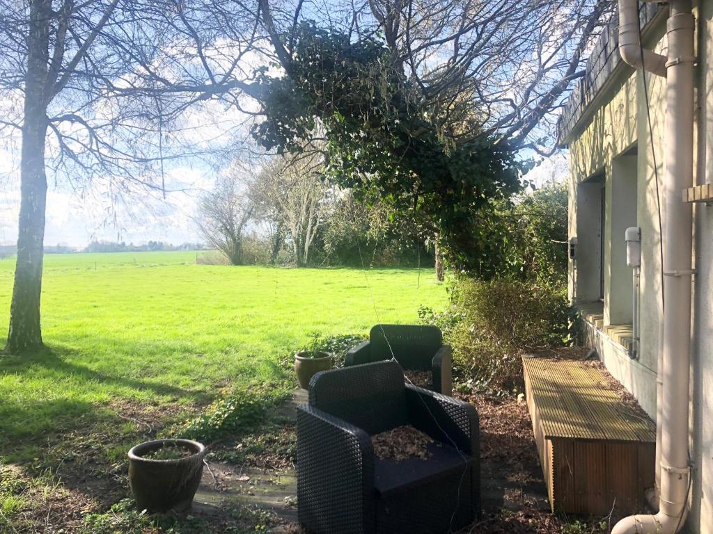 Zwei Stühle stehen vor einem Haus mit einem Feld in der Unterkunft APPARTEMENT 3 LITS Parking Proche Rouen Dock in Canteleu