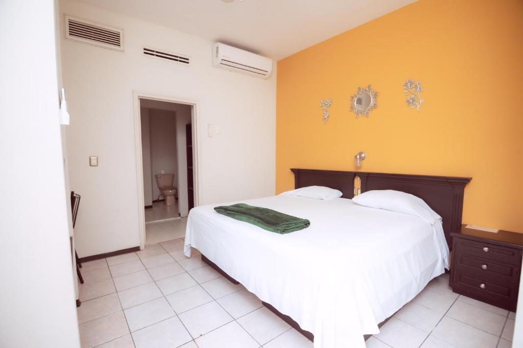 ein Schlafzimmer mit einem weißen Bett und einer gelben Wand in der Unterkunft Nova Departamentos in Cadereyta Jiménez